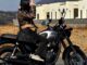 A woman on a Triumph motorcycle wearing a dark oak Builford Classic Hobo messenger bag.