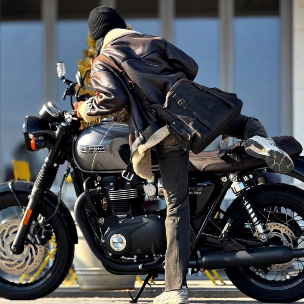 Action shot of a rider mounting a motorcycle with the Builford Classic Hobo bag positioned securely on their back.